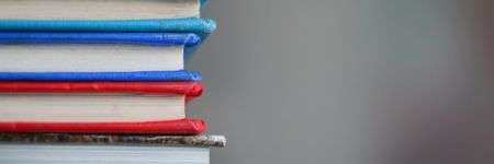 Spalvotų knygų stulpelis prieš miglotą foną.