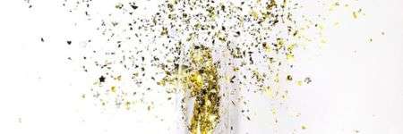 Šampano taurė su auksiniais ir sidabriniais konfeti.