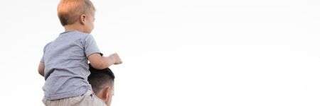 Vaikas ant pečių prieš šviesų foną, vaizduojantis pasitikėjimą.