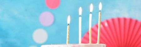 Tortas su žvakutėmis ir šiltas, linksmas dekoras fone.