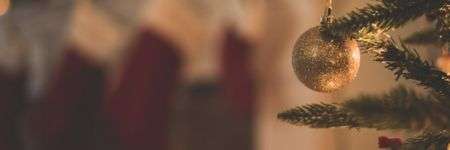 Eglė su auksiniais kamuoliais ir raudonomis kojinėmis, kuriančiomis šventinę atmosferą.